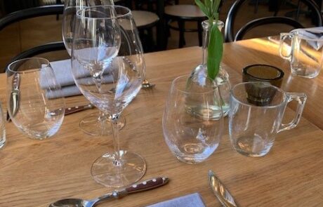 Dukat bord med vinglas och grå servett samt en fin blomma i vas
